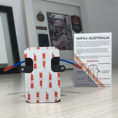 MiFire Sentry wireless automatic fire extinguisher rear showing double sided tape and zip tie eyeletsFire Fighter picture in background. MiFire Australia.